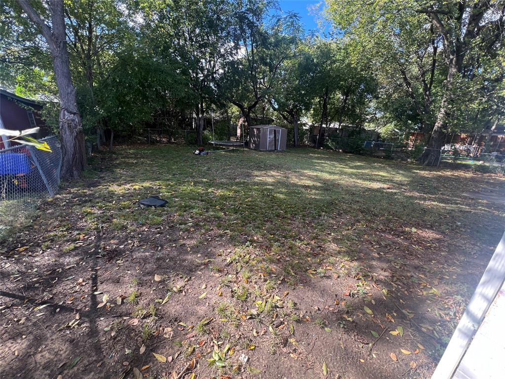 1722 Proctor Street Grand Prairie, TX 75051 - Photo 36 of 39 Fenced backyard featuring a shed and view of wooded area