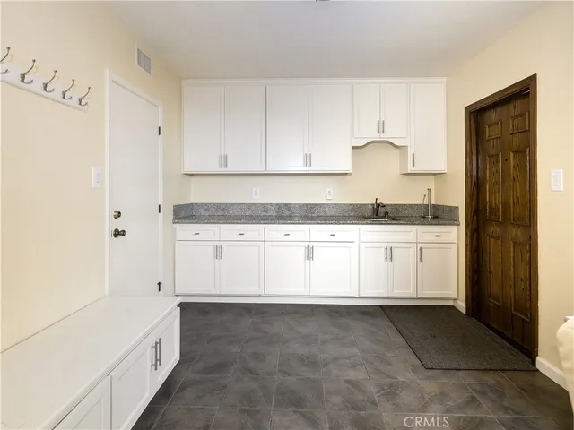 a large white kitchen with granite countertop white cabinets and sink