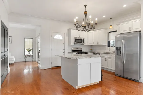 a kitchen with kitchen island white cabinets and stainless steel appliances