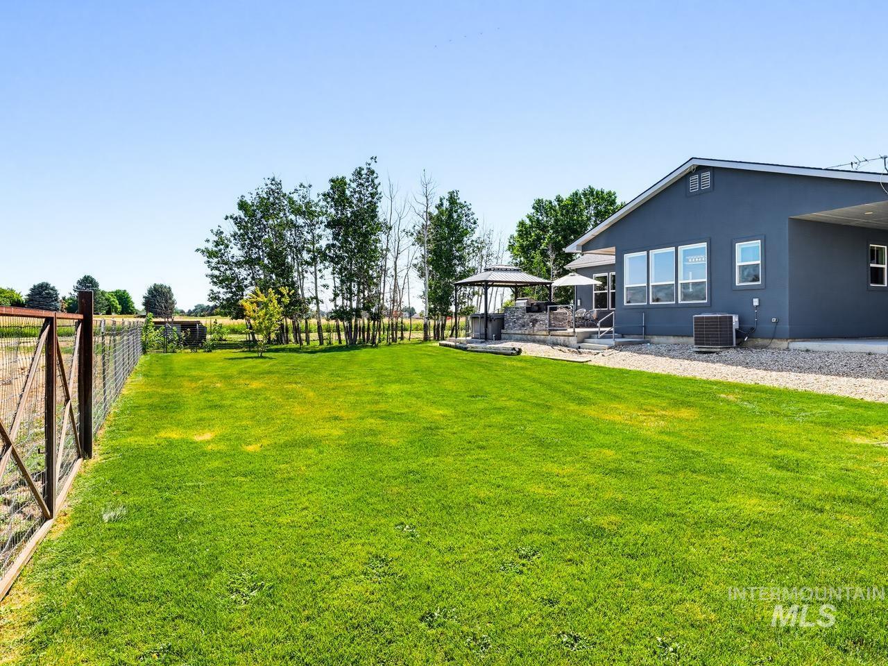 4950 West Columbia Road Nampa, ID 83687 - Photo 45 of 50 Expansive outdoor area featuring a lush green lawn, mature trees, and a perimeter fence