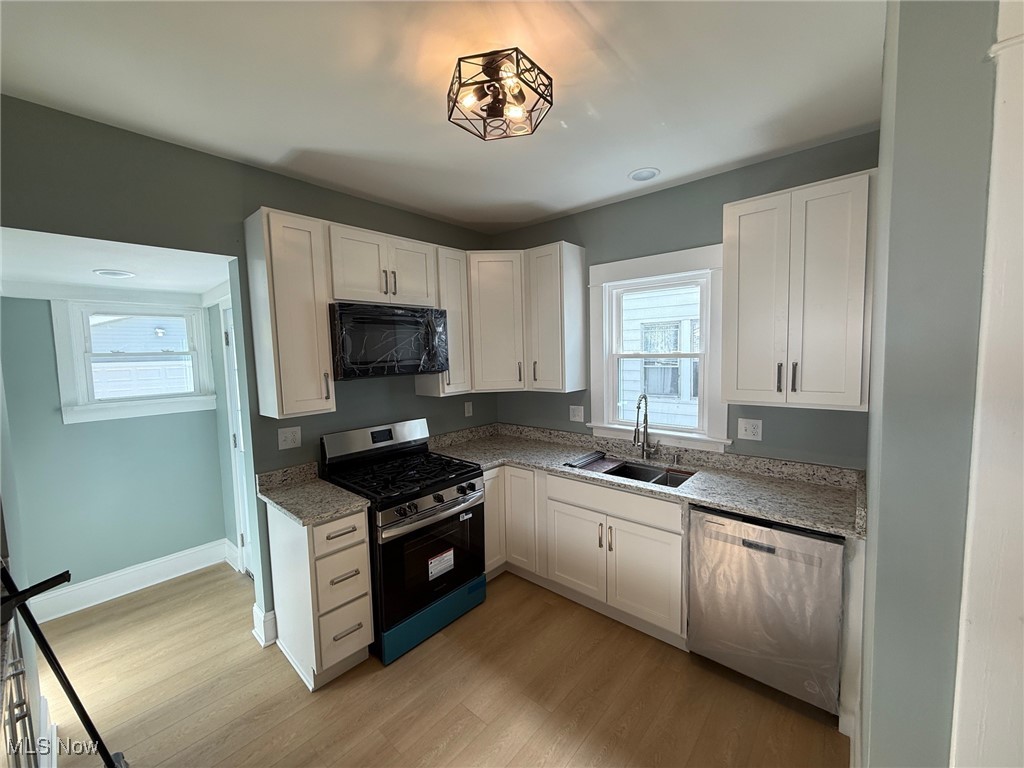 2185 Rexwood Road Cleveland, OH 44118 - Photo 7 of 26 Kitchen with appliances with stainless steel finishes, white cabinets, light wood-style flooring, light stone counters, and healthy amount of natural light