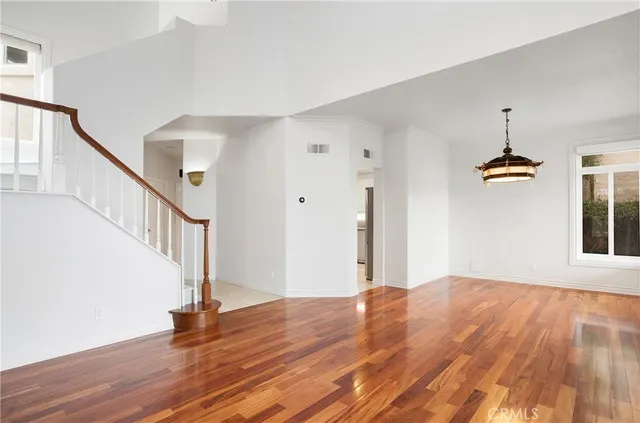 a view of an empty room with wooden floor and stairs