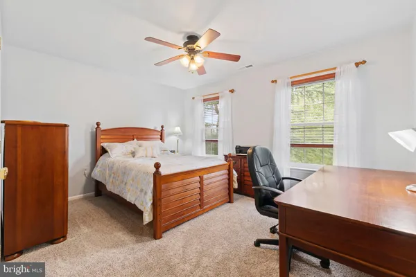 a bathroom with a toilet a sink a mirror and a window