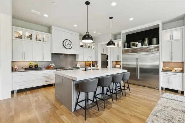 a kitchen with stainless steel appliances kitchen island granite countertop a stove a sink a oven a dining table and chairs with wooden floor