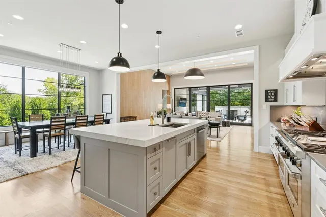a kitchen with kitchen island a counter a stove a sink a dining table and chairs with wooden floor