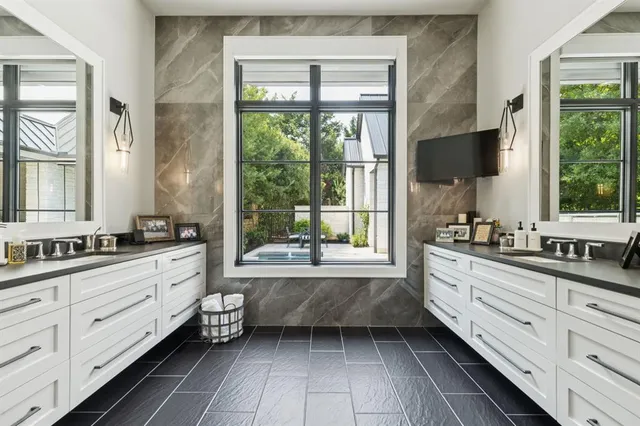 a large bathroom with a double vanity sink a large mirror and a bathtub next to a window
