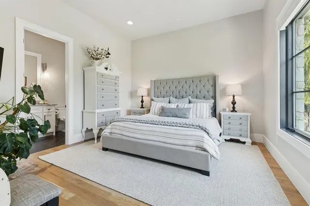 a spacious bedroom with a bed a mirror and potted plant