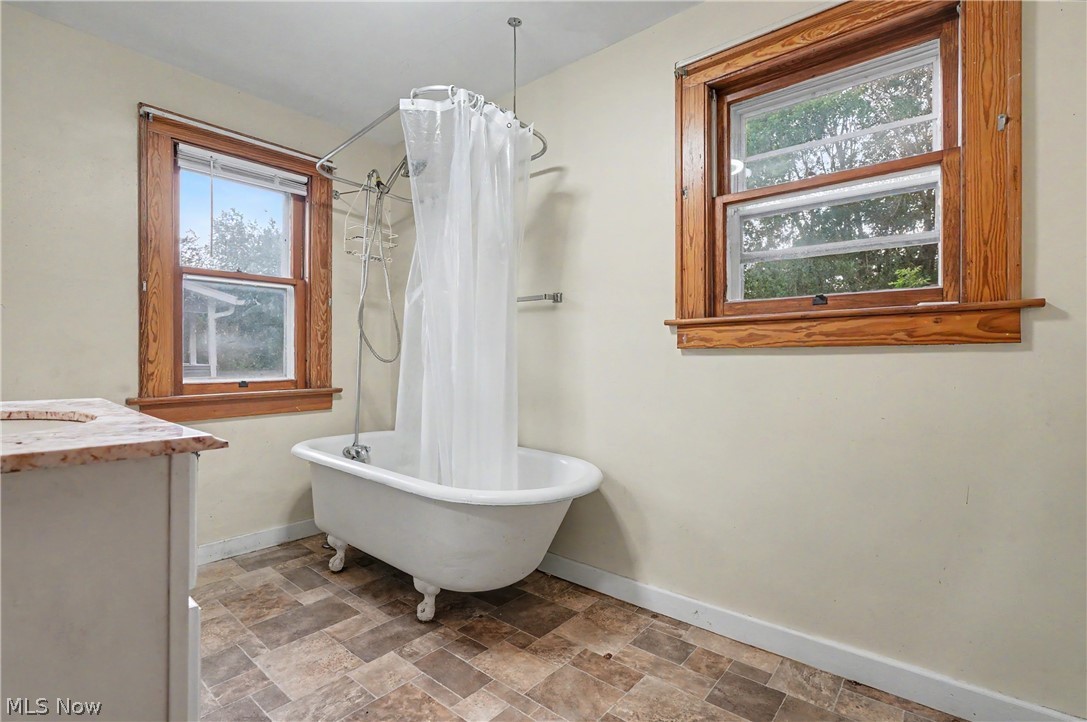 456 Delmar Avenue Akron, OH 44310 - Photo 16 of 27 Freestanding clawfoot tub with shower attachment, complemented by two windows featuring natural wood trim