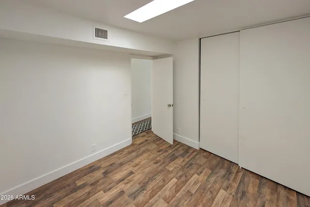 a view of an empty room with wooden floor and closet