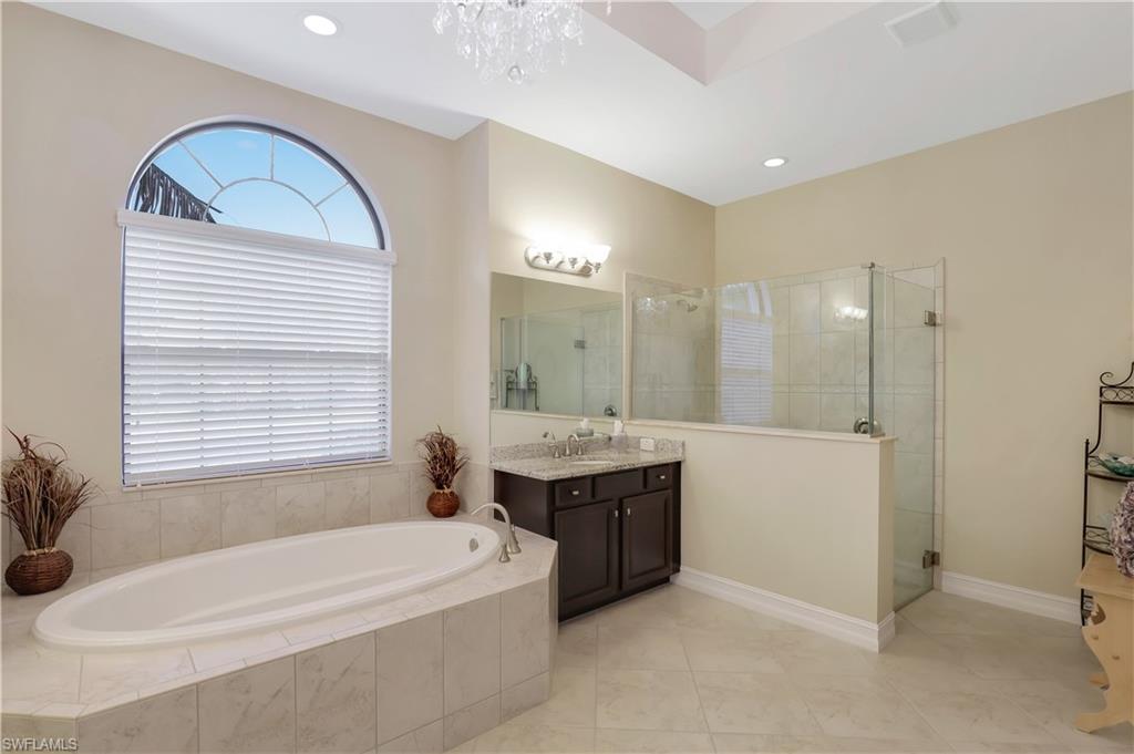 Undisclosed Address Naples, FL 34120 - Photo 13 of 33 a bathroom with a bathtub a double vanity sink and mirror