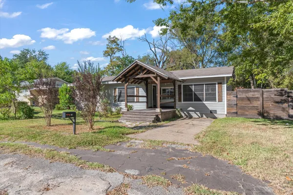 a view of a yard in front of a house with a large tree