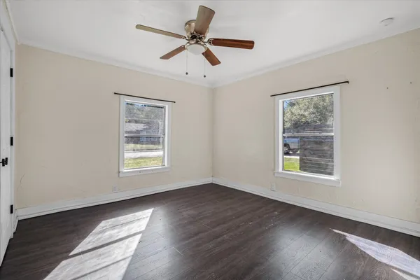 a view of an empty room with wooden floor and a window