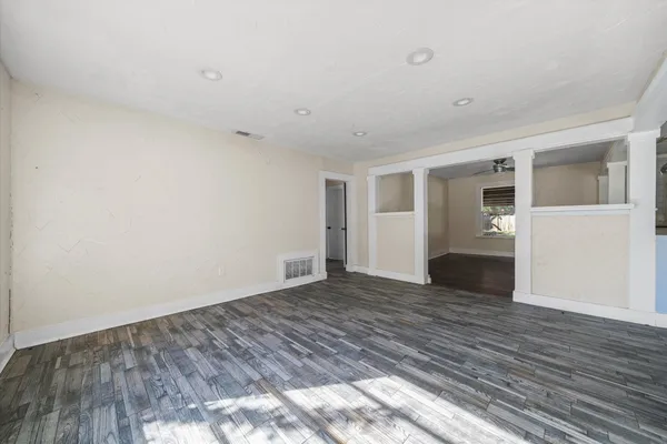 a view of an empty room with wooden floor and a window