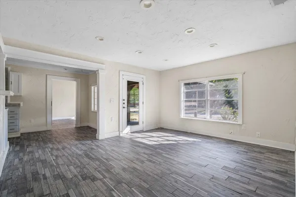 a view of an empty room with wooden floor and a window