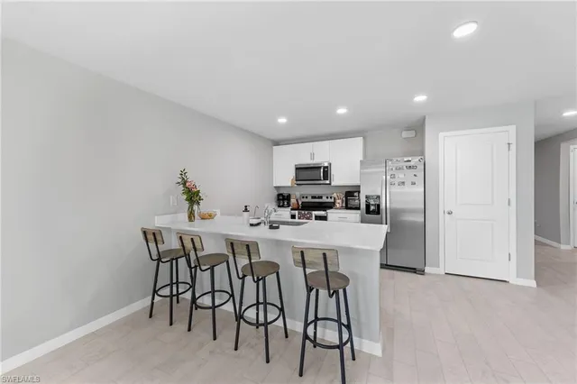 a kitchen with stainless steel appliances a white table chairs and a refrigerator