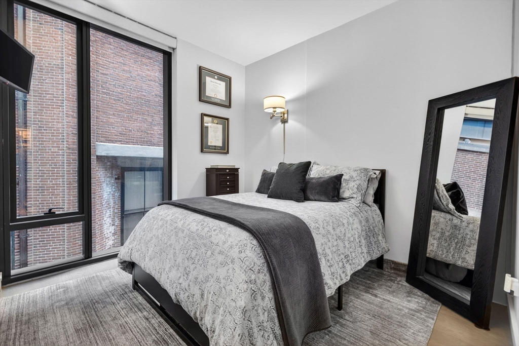 55 Lagrange Street, Unit 409 Boston, MA 02111 - Photo 10 of 29 a bedroom with a bed and a mirror