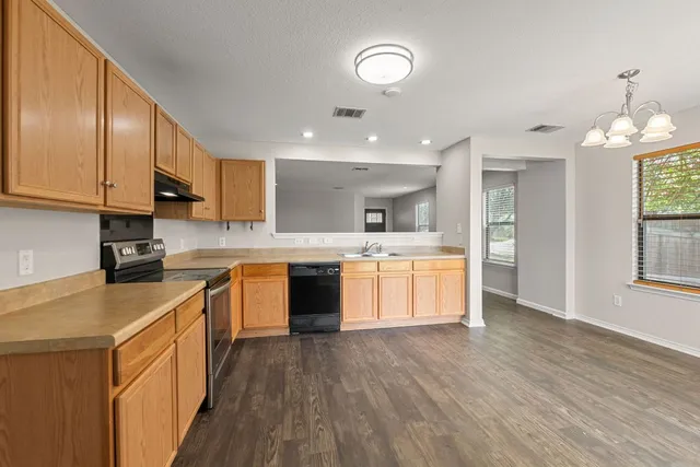 a large kitchen with stainless steel appliances granite countertop a stove a sink dishwasher and a refrigerator with wooden floor