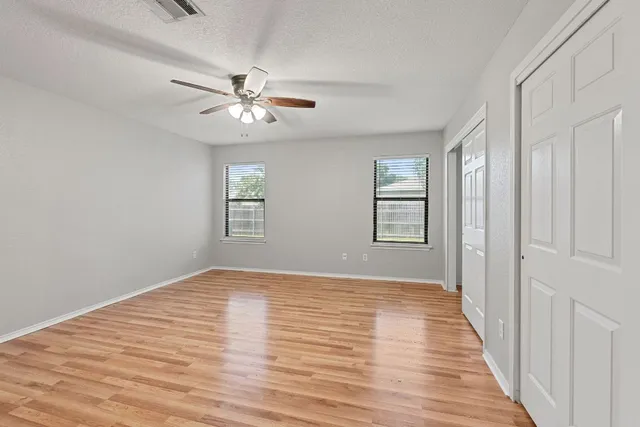 a view of an empty room with window and wooden floor