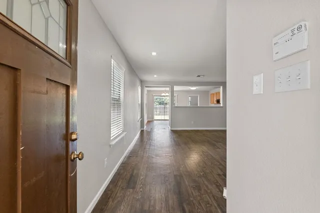 a view of a hallway with wooden floor and a bathroom