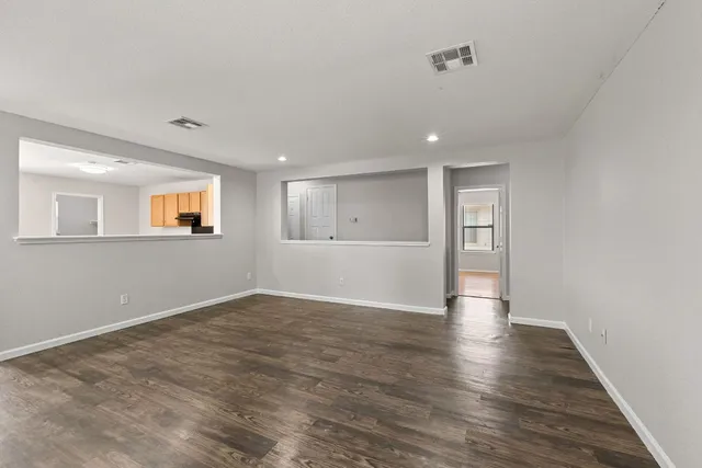a view of an empty room with wooden floor and windows