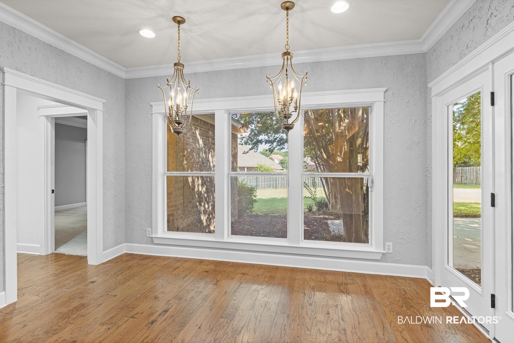 11261 Halcyon Loop Daphne, AL 36526 - Photo 12 of 41 Spacious room featuring wood-finish flooring, light grey textured walls, and a large multi-pane window