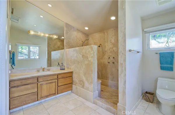 a bathroom with a granite countertop sink a toilet a mirror and shower