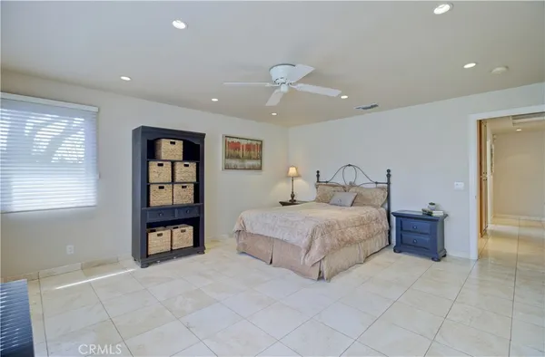 a spacious bedroom with a bed a dresser and a window