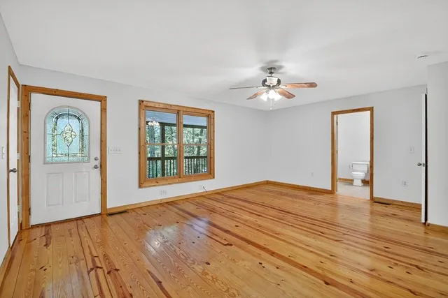 a view of an empty room with window and wooden floor