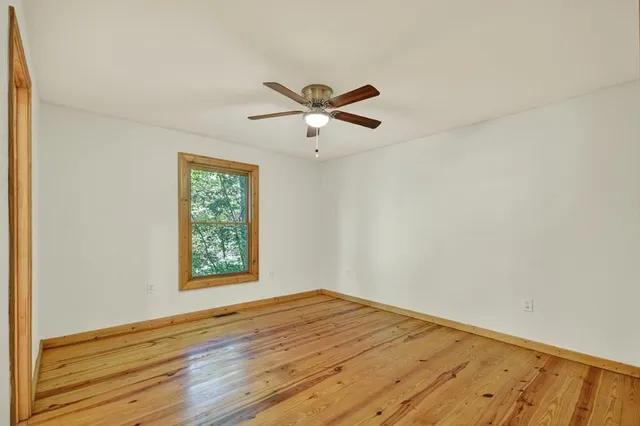 a view of a room with wooden floor and a ceiling fan