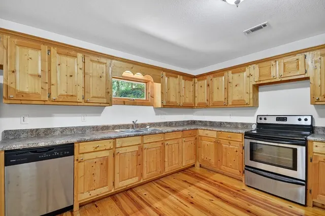 a kitchen with granite countertop a stove sink and cabinets