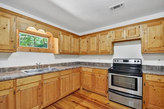 a kitchen with granite countertop cabinets stainless steel appliances and a window