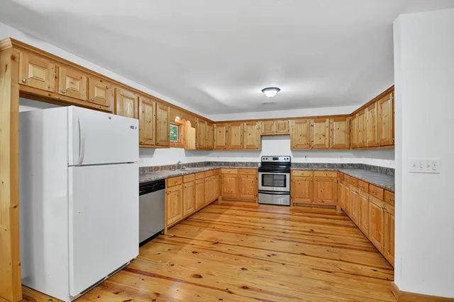 a kitchen with stainless steel appliances granite countertop a refrigerator and a stove top oven