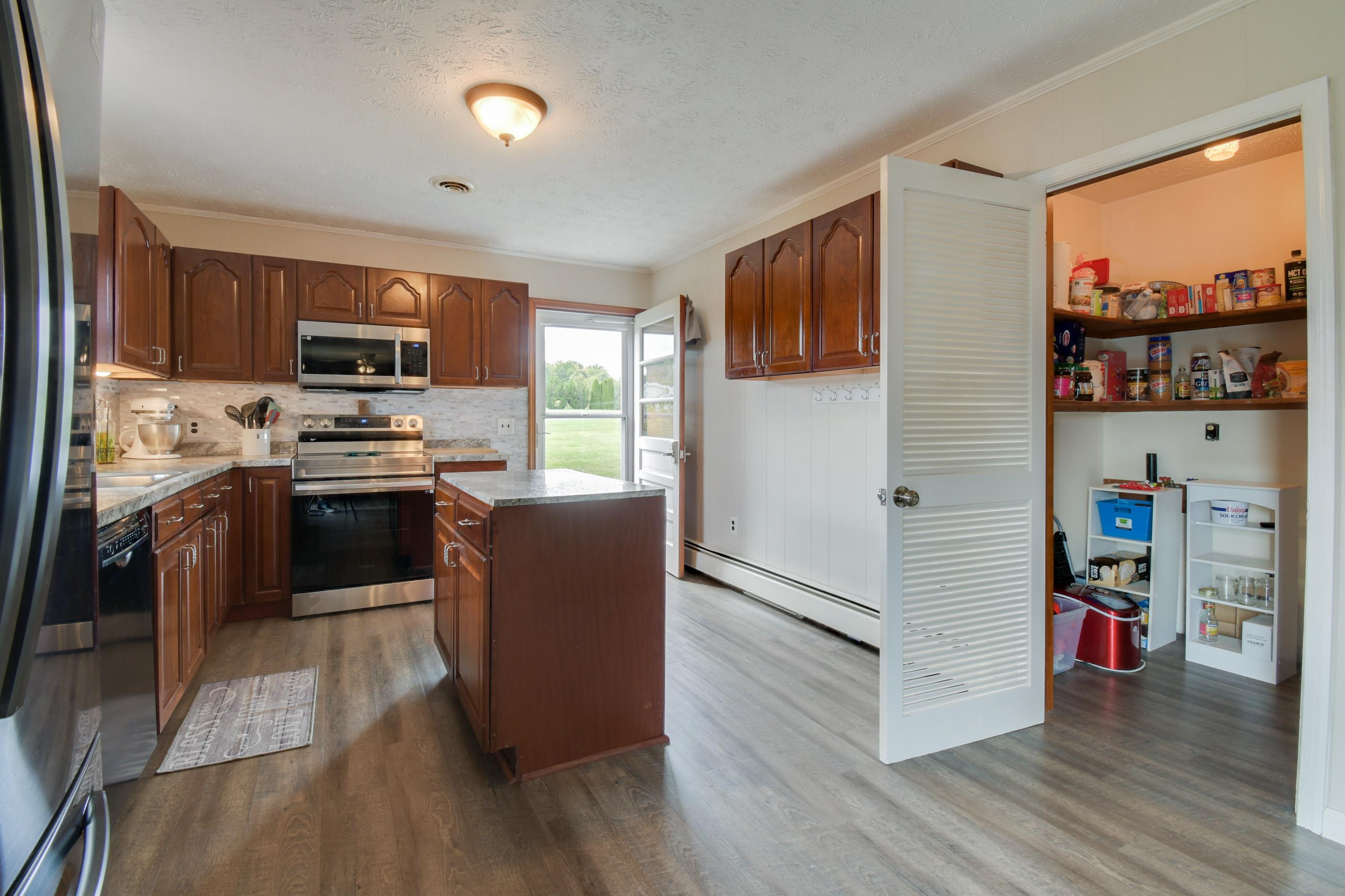 263 Craig Shop Road Mount Sidney, VA 24467 - Photo 4 of 25 a kitchen with stainless steel appliances granite countertop a stove top oven a sink dishwasher a refrigerator and a dining table with wooden floor