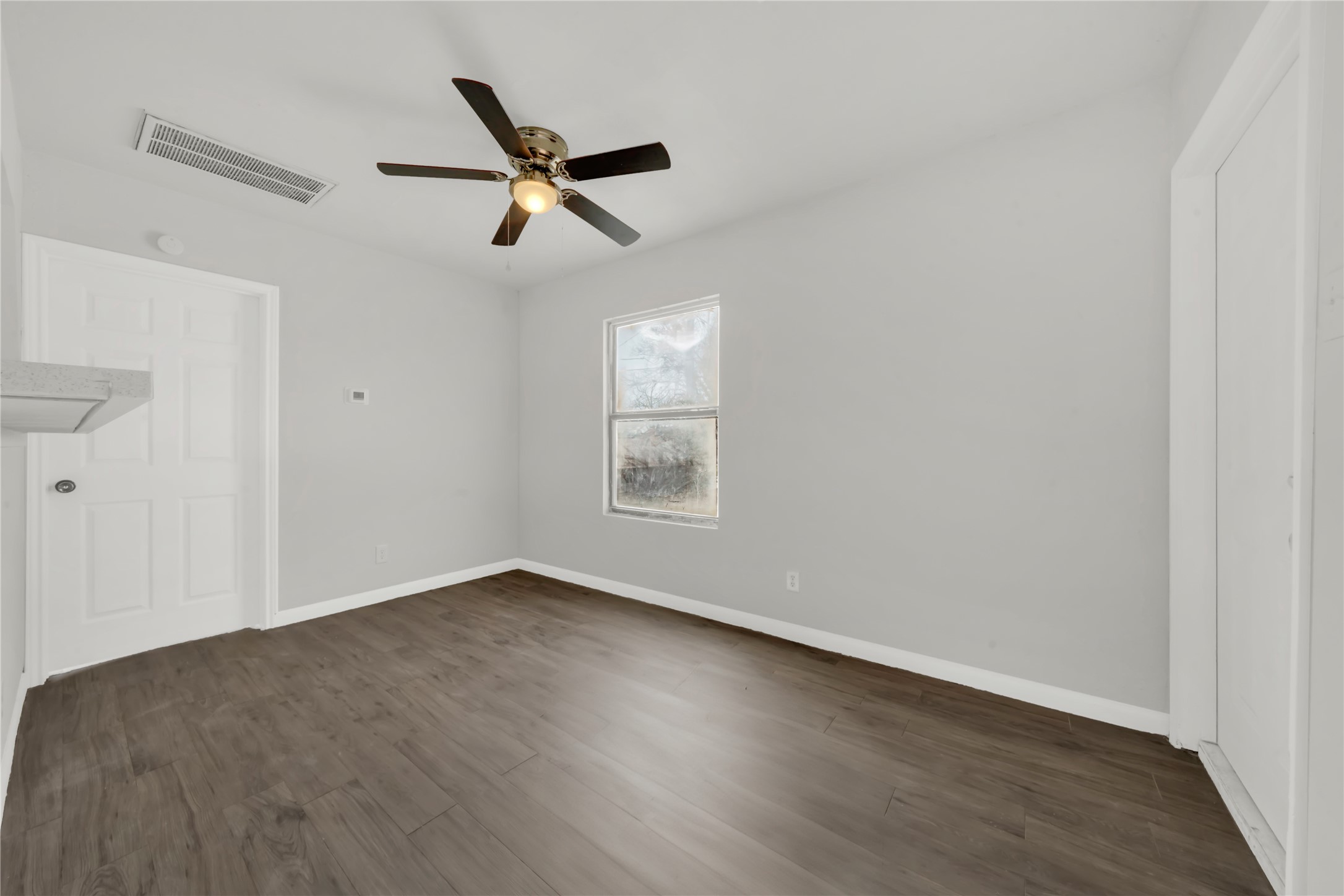 106 Hanover Street Houston, TX 77012 - Photo 38 of 49 an empty room with wooden floor ceiling fan and windows