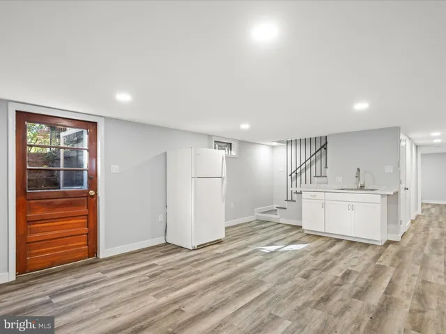 a large white kitchen with wooden floor and a sink