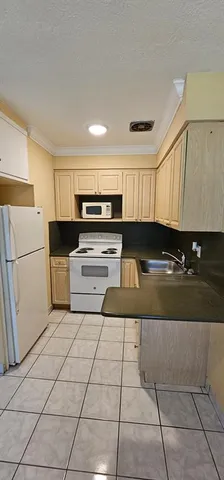 a kitchen with a sink a stove top oven and white cabinets