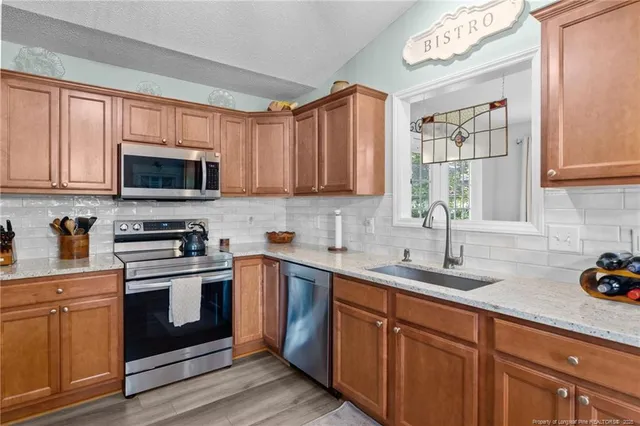 a kitchen with stainless steel appliances granite countertop a sink a stove and cabinets