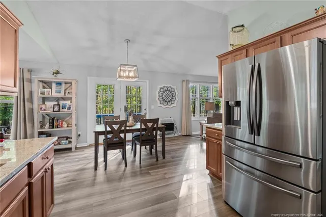 a kitchen with stainless steel appliances granite countertop a refrigerator a stove a dining table and chairs with wooden floor