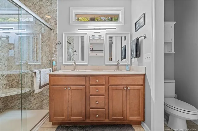 a bathroom with a granite countertop sink a toilet a mirror and shower