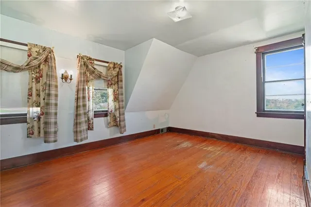 a view of an empty room with window and wooden floor