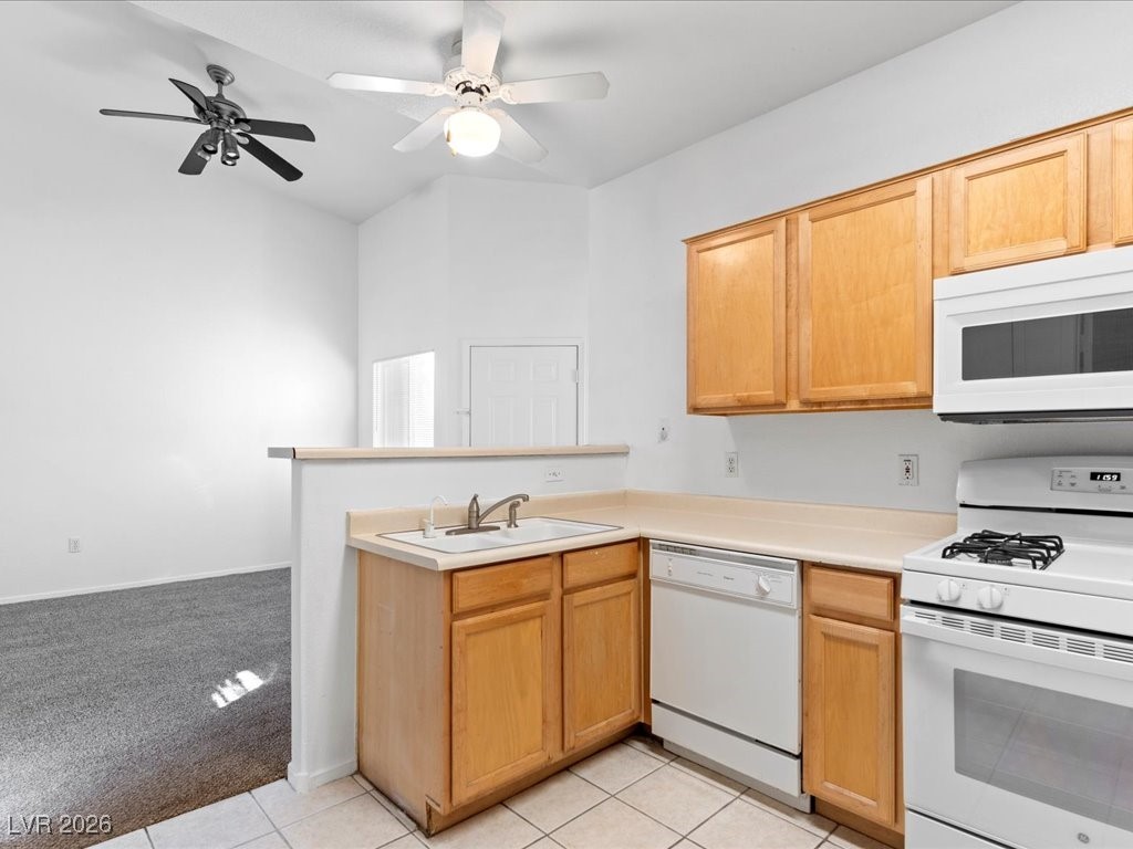 8725 West Flamingo Road, Unit 235 Las Vegas, NV 89147 - Photo 19 of 22 Kitchen featuring white appliances, a peninsula, light countertops, light carpet, and light tile patterned floors