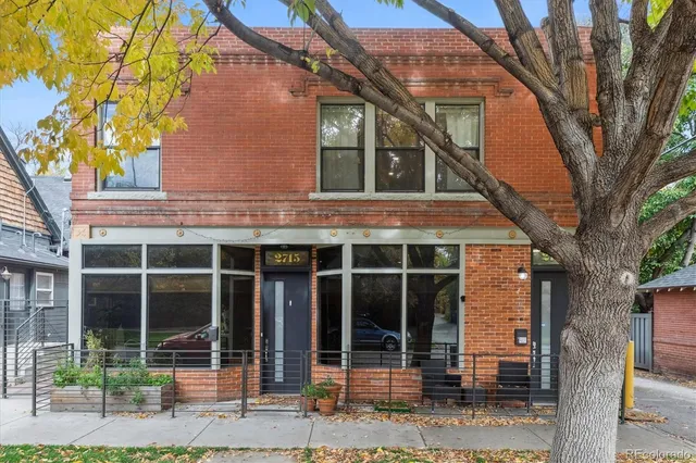 a view of brick house with large windows and a large tree