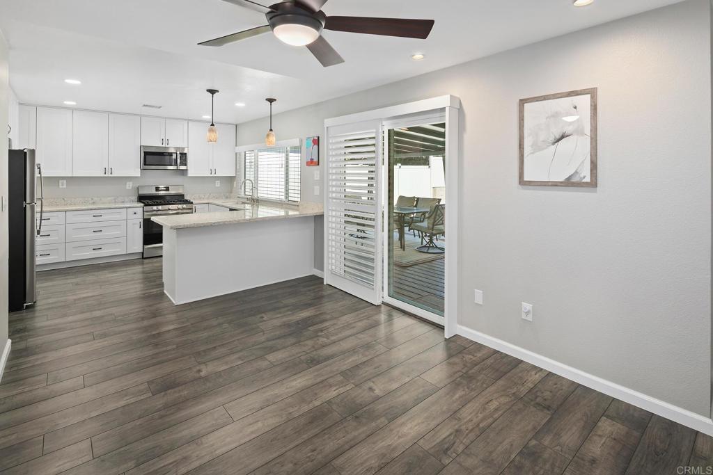 10033 Woodpark Drive Santee, CA 92071 - Photo 7 of 21 a kitchen with wooden floors and white cabinets