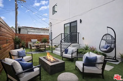 a living room with furniture potted plant and kitchen view