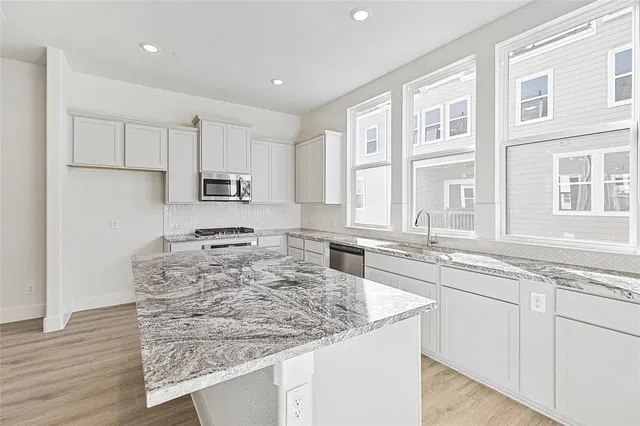 a kitchen with stainless steel appliances granite countertop a sink stove and cabinets