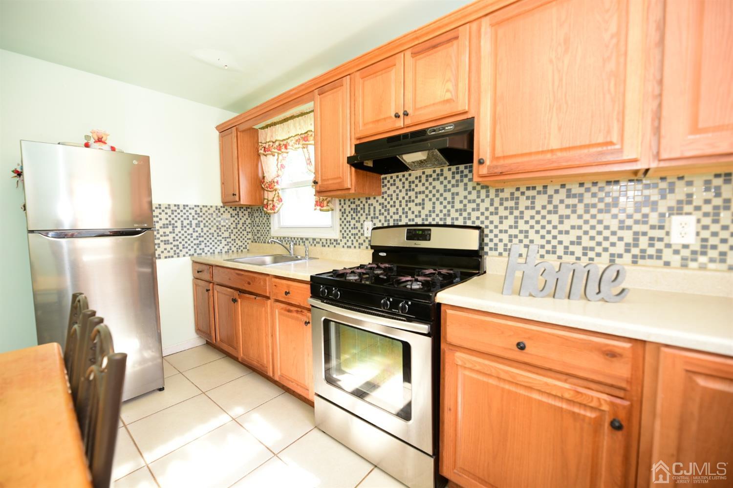 103 Tunison Road New Brunswick, NJ 08901 - Photo 14 of 30 a kitchen with granite countertop a stove top oven cabinetry a sink and a refrigerator