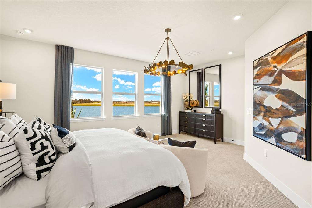 12785 Jade Empress Loop, Unit 202 Venice, FL 34293 - Photo 22 of 42 a bedroom with a bed a dresser and a chandelier