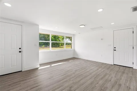 a view of an empty room with wooden floor and windows