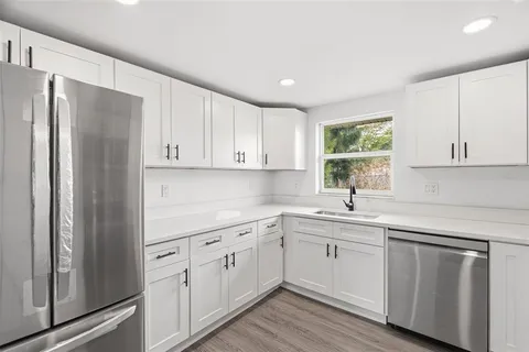 a kitchen with white cabinets white appliances and sink