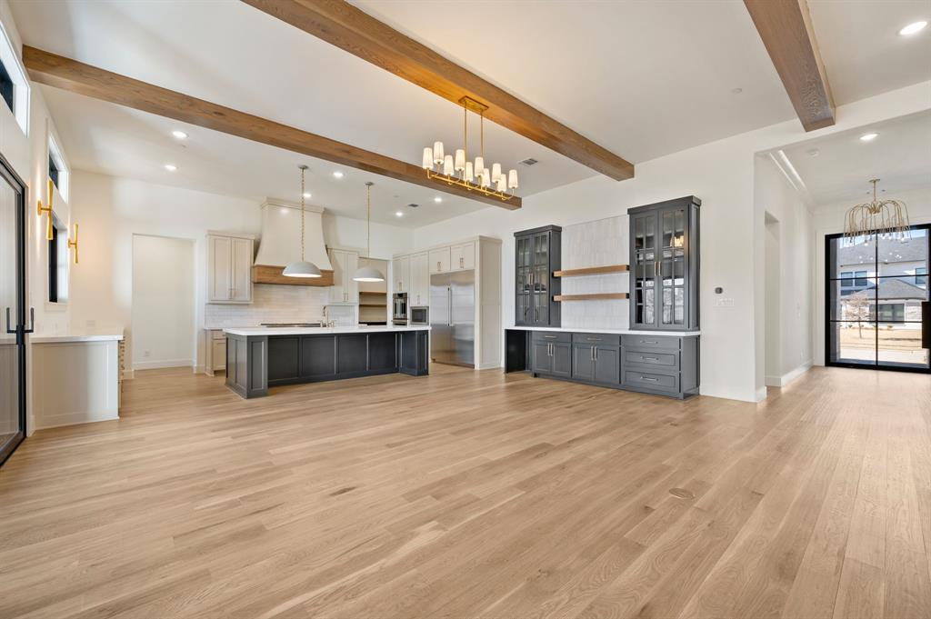 1460 Copper Point Drive Prosper, TX 75078 - Photo 11 of 40 a large kitchen with stainless steel appliances kitchen island a large counter top and a wooden floor